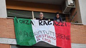 Sång, dans och klappningar invid banderoller (med texterna "Kom igen människor,#alltkommerattblibra, "vi stannar hemma") under flash mob-tilldragelsen "Una canzone per l'Italia" ("En sång för Italien" ) i distriktet Magliana i Rom 15.3.2020. Uppmuntrande texter på balkonger i distriktet Magliana i Rom 15.3.2020