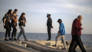 En polis i skyddsmask övervakade flanörer vid en strand utanför Aten på lördagen. En polis i skyddsmask övervakade flanörer vid en strand utanför Aten på lördagen.