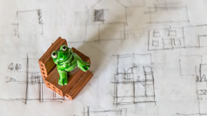 Placera in sovrummen nära varandra om du får vara med i planeringen från början. leksaksgroda sitter på små tegelstenar på handritad bostadsriting