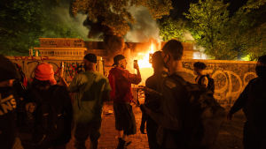 Demonstranter står intill en brinnande byggnad i Lafayette-parken, nära Vita huset. En del bilar stacks också i brand. Demonstranter står intill en brinnande byggnad i Lafayette-parken, nära Vita huset. En del bilar stacks också i brand.