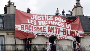 Invånare försöker riva loss en banderoll med texten "offer för anti-vit rasism" som extremhögern placerat på en byggnad nära Place de la Republique i Paris. 13.6.2020 Invånare försöker riva loss en banderoll med texten "offer för anti-vit rasism" som extremhögern placerat på en byggnad nära Place de la Republiquei Paris. 13.6.2020
