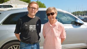 Pertti Soini och Sinikka Soini skulle sänka roderfyllerigränsen till noll promille. En ljushårig man klädd i svart t-skjorta, jeans och glasögon, och en ljushårigkvinna klädd i ljusröd t-skjorta, jeans och solglasögon står framför en parkerad bil.