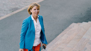 Justitieminister Anna-Maja Henriksson. Anna Maja Henriksson i blå kavaj och storblommiga byxor. Hon går upp för en trappa.
