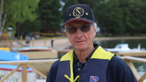 Bjarne Ölander har sett motorbåtarna växa för varje år som går. Kunskap är det som förhindrar olyckor anser Ölander. Äldre herre står med flytväst på brygga i Nagu gästhamn och tittar.
