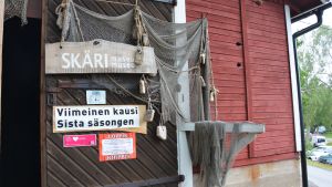 En dörr till en gammal träbyggnad som är inramad av fiskenät och med en skylt som säger 'Skärimuseum sista säsongen'.