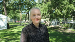 Jenna Fyhr, evenemangsproducent för Aura Fest, säger att man från arrangörernas sida till och med gör mer än vad som krävs med tanke på coronaläget. En kvinna i prickig blus står i Kuppisparken och ler.