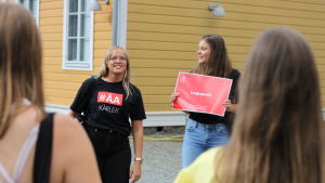 Tutorerna samlar ihop sina förstaåringar. En kvinna med en röd skylt där det står "logopedi" och en kvinnlig tutor.