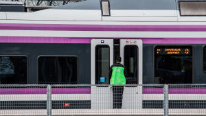 Spårtrafiken ska utvecklas i stora delar av Nyland. Arkivbild. Pendeltåg på station. Tågvärd väntar på att dörren ska öppnas.