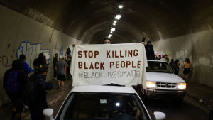Black Lives Matter-demonstrationerna har ebbat ut under sommaren, men fallet med Jacob Blake kan ge nytt bränsle åt ilskan. Demonstranter står i en tunnel. Två vita bilar syns på bilden över den bilens tak håller en demonstrant ett plaket med texten "Stop killing black people".