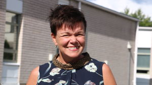 Projektledaren Annette Kronholm-Cederberg vill få lärarna att lära sig av varandra. En leende kvinna med kort mörkt hår kisar. I bakgrunden syns en grå tegelbyggnad.