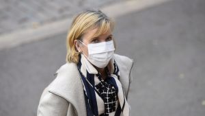 Anna-Maja Henriksson på väg in i Ständerhuset 14.10 Kvinna med ljust hår och munskydd ser in i kameran. Kvinnan är justitieminister Anna-Maja Henriksson.