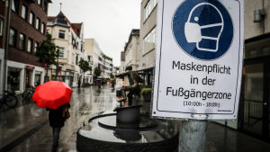 En skylt som uppmanar till att bära ansiktsskydd ifall man rör sig i området vissa tider. En skylt med texten "ansiktsskyddsplikt" på tyska