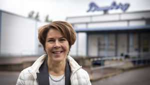 Brunbergs vd Katarina Enholm tror på framtiden. Arkivbild. Leende kvinna står framför fabriksbyggnad. På en suddig skylt i bakgrunden står det Brunberg.