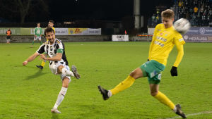 Det blev ett känslosamt farväl till hemmafansen för TPS-kaptenen Sami Rähmönen (till vänster i bild). Fotbollsspelare skjuter ett hårt skott mot annan spelare på fotbollsplan under pågående match.