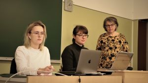 Frida Rosenback och Camilla Norrgård jobbar på sin appidé under läraren Margita Engelholms vakande öga. Två flickor sitter framför var sin dator. Bredvid ena flickan står en kvinna.