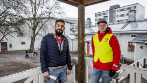 Al-dabbach och Kullberg tycker att det är roligt att jobba på Sirkkala skola. Två män iklädda puffjackor står på terass ute på en skolgård en regnig dag.