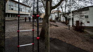 Skolvardagen fortlöper som vanligt på Sirkkalas skolgård, trots coronavirusepidemin. Molnig och regnig dag på en lågstadieskolgård. En grupp barn går mot vit matsalsbyggnad.
