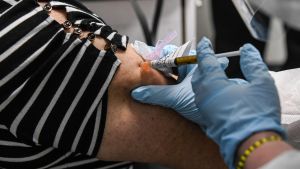 Hela planeten kan inte få vaccinet på en gång. Kvinna får tesetvaccin i augusti. Florida, USA.
