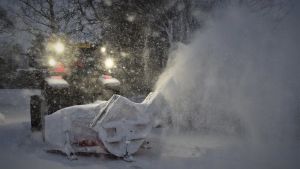 Traktor med snöplog som sprutar snö.