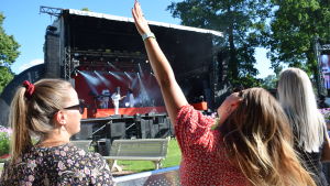 I somras ordnades bara ett fåtal festivaler, men en del blev ändå smittade, men också på vintern har folk smittats på fester. En festivalbesökare sträcker upp ena handen mot himlen och njuter av musik som kommer från en scen utomhus.