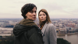 Rita (Lotta Lehtikari) ja Laura (Niina Koponen) katsovat olkansa yli huolestuneen näköisinä kaupunkimaisena taustallaan.