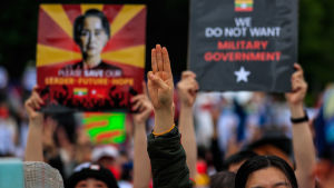 En aktiv opposition ökar sannolikheten för att sanktioner ska få önskad effekt. En demonstrant lyften tre fingrar i Myanmar. I bakgrunden syns två skyltar.