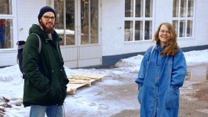 Konstnärerna Risto Musta och Taru Samola. en man och en kvinna framför ljus byggnad och snö
