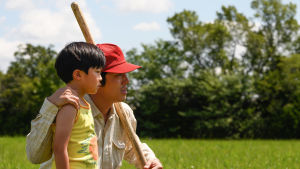 David (Alan S. Kim) och Jacob (Steven Yeun) är säkra på att de kan hitta vatten genom att tänka smart och iaktta landskapet. Jacob (Steven Yeun) står med sin David (Alan S. Kim) vid en åkerkant. Jacob ser glad och nöjd ut.
