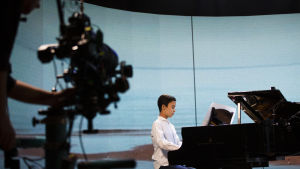 Den stora utmaningen med Skolmusik 2021 var att skapa en stor gemensam musikupplevelse men göra det coronasäkert. En kamera filmar en tonårspojke som spelar flygel på Schaumanscenen i Jakobstad.