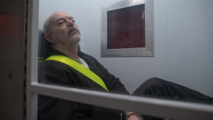 Keith Allen näyttelee John Cooperia sarjassa Pembrokeshiren murhat. Keith Allen nojaa seinään.
