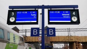 Informationstavlor visar att det är stora förseningar i tågtrafiken. Till vänster syns ett grönvitt Intercitytåg.