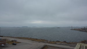 Lastningsplanen byggs från det röda huset vid stranden som syns i nedre vänstra hörnet och fortsätter snett uppåt till höger. Vågbrytaren byggs från huset i nedre hörent till sjömärket på ändan av udden.