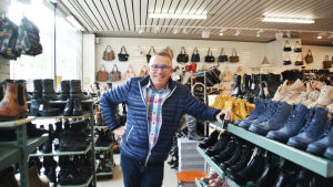 Tapio Viljanens skobutik går bra på Kungsgatan. En bild på en man i blå rock som står mellan hyllor fyllda med skor. I bakgrunden hänger väskor på en vägg. Mannen är Tapio Viljanen.