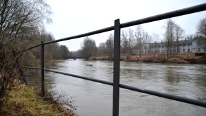 Svartån vid Billnäs bruk. En bild på en å och ett staket som står bredvid den.