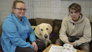 Happy hjälper bland annat Jerker Storbäck att läsa finska. Här sitter de tillsammans med specialläraren Helena Isuls Kvinna, hund och pojke