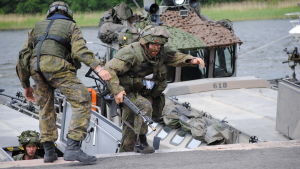 Innan bostadsbyggandet började, kunde försvaret också öva på det stora området. Foto från 2013. Militärer övar landstigning i terrängsdräkter med vapen. Män tar i land från en båt.