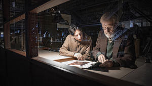 Otto (Amos Brotherus) och Olavi (Heikki Nousiainen) har startat detektivarbetet. Otto (Amos Brotherus) och Olavi (Heikki Nousiainen) sitter i arkivet och tittar på gamla utställningskataloger.