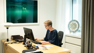 Krista Mikkosen työhuoneen seinää koristaa vielä edellisen ympäristöministeri Kimmo Tiilikaisen valitsema teos. Krista Mikkonen työpöytänsä ääressä.