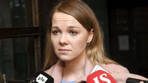 Centerledaren Katri Kulmuni undvek direkta kommentarer 2.12.2019 Katri Kulmuni, en ung kvinna med blont hår och en rosa jacka blir intervjuad framför en mörk vägg. I förgrunden syns två stycken stora mikrofoner och ett par ljudinspelare.