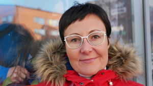 Sanna Kärkkäinen är nöjd över det goda rykte som Rovaniemi och Lappland har i världen. Närbild på Visit Rovaniemis VD utanför kontoret. Hon har röd jacka, svart kort hår och glasögon med vita bågar.