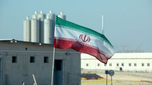 Iran hotar med att kärnkraften snart inte är enbart för fredligt bruk. Irans flagga vajar framför iranskt kärnkraftverk.
