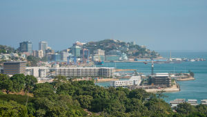 Papaua-Uusi-Guinean pääkaupunki Port Moresby Kaupunkimaisema Port Moresbystä, etualalla puita.