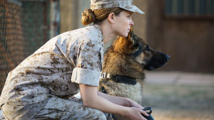 Megan Leavey. Nainen sotilaspuvussa istuu penkillä vieressään saksanpaimenkoira.