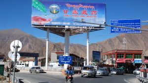 Till och med i avlägsna Tibet kantas landsvägarna av reklamskyltar. På den här gör ett privatföretag reklam för sina traditionella läkemedel. En stor reklamskylt på kinesiska i en vägkorsning
