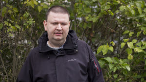 2006 blev synen sämre för Andreas, men han saknar ändå inte att kunna se till exempel bilder. Information är viktigare. Andreas Kanto står framför en buske som har gröna löv. Han har på sig en svart jacka.