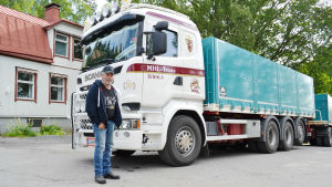 Magnus Lindgren driver familjeföretaget MHL trans i Tenala tillsammans med sin bror. De har ungefär 30 anställda. En man står brevid en vit lastbil med grönblå vagn. Mannen har en svart tröja och en svart keps på sig. I bakgrunden syns ett hus.