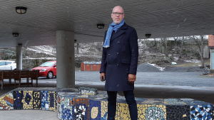 Elevhandledare Kim Johansson man i fyrtioårs-åldern står bredbent på skolgård med ljusblå halsduk och mörkblåa kläder
