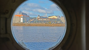 Från m/s J.L. Runebergs plats vid bryggan har man utsikt mot Konstfabriken på andra sidan ån. Kabelfabriken genom ett fönster på fartyget m/s j.l. Runeberg