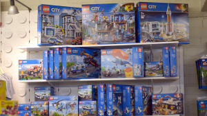 Daméns favoritleksak lego hör hemma på butikens hyllor. Legoleksakslådor är uppstaplade på en grupp hyllor.