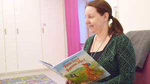 Charlotta Blomqvist sitter med en Mamma Mu-bok i handen.